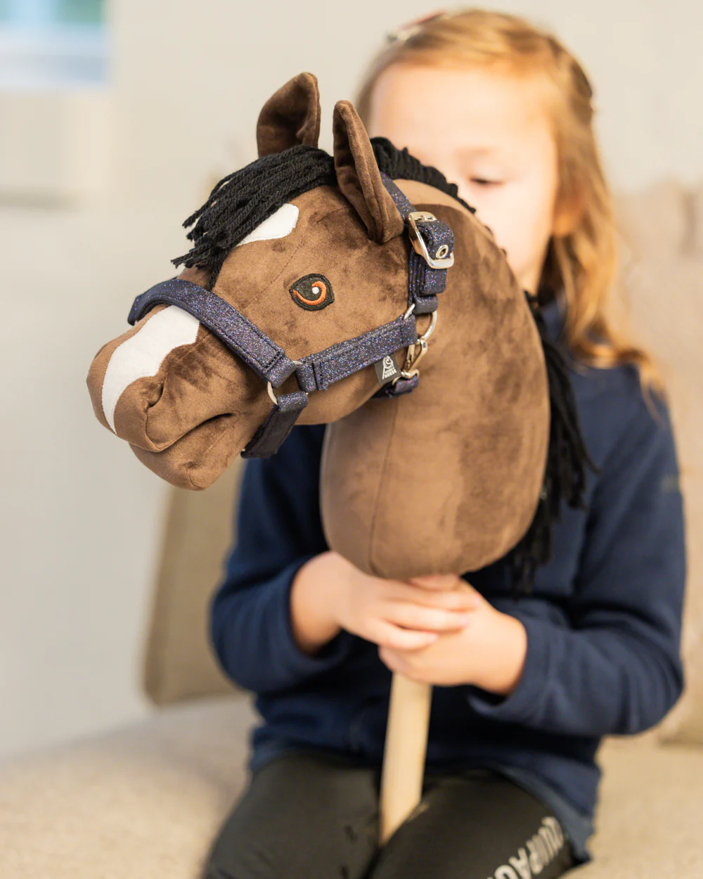 Meisje met bruin hobbyhorse met blauw navy glitter halster